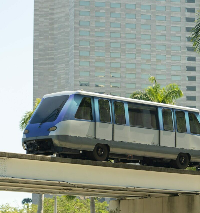 Public transportation in downtown Miami in Florida USA. Metrorail city train car on high railroad over street traffic between skyscraper buildings in modern American megapolis Public transportation in downtown Miami in Florida USA. Metrorail city train car on high railroad over street traffic between skyscraper buildings in modern American megapolis.
